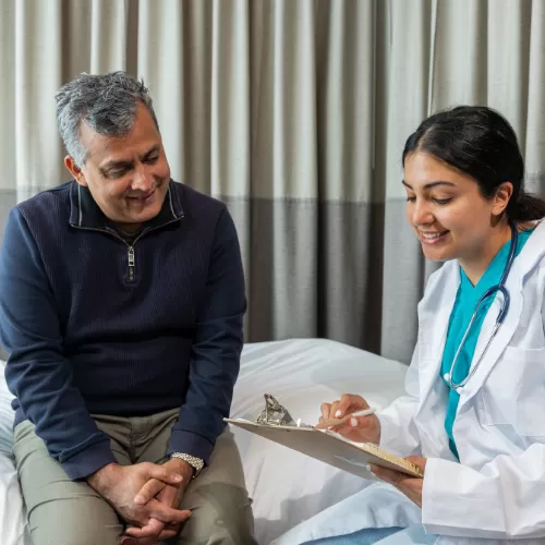 Profesional de la salud conversando con adulto mayor durante atención geriátrica a domicilio en Santiago